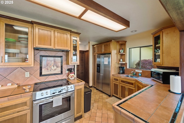 1230 Seagate Ave, Coos Bay, OR 97420 - kitchen featuring appliances with stainless steel finishes, tile counters, tasteful backsplash, a sink, and light tile patterned floors