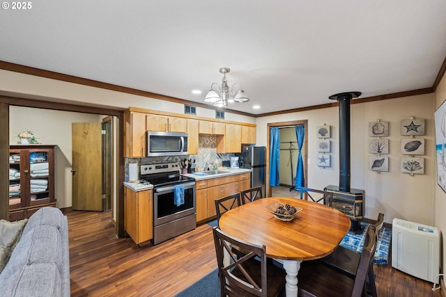1230 Seagate Ave, Coos Bay, OR 97420 - kitchen with appliances with stainless steel finishes, tasteful backsplash, light countertops, a sink, and a wood stove