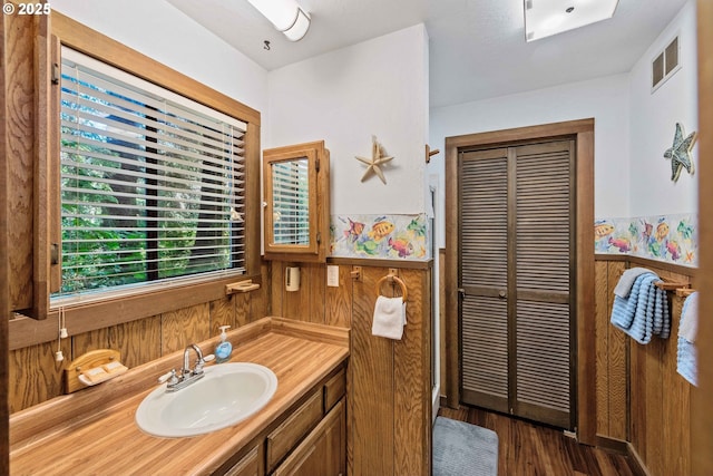 1230 Seagate Ave, Coos Bay, OR 97420 - bathroom featuring vanity, a closet, wood finished floors, wooden walls, and wainscoting