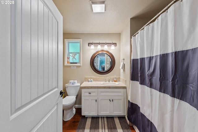 1230 Seagate Ave, Coos Bay, OR 97420 - bathroom featuring toilet, vanity, wood finished floors, and a textured ceiling