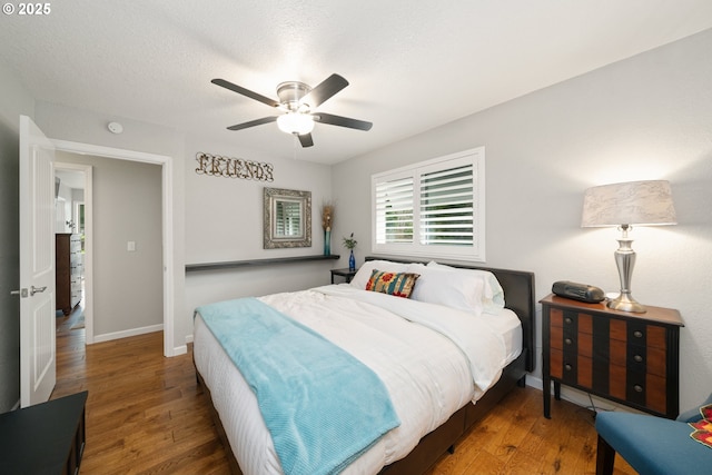 bedroom featuring a textured ceiling, wood finished floors, a ceiling fan, and baseboards