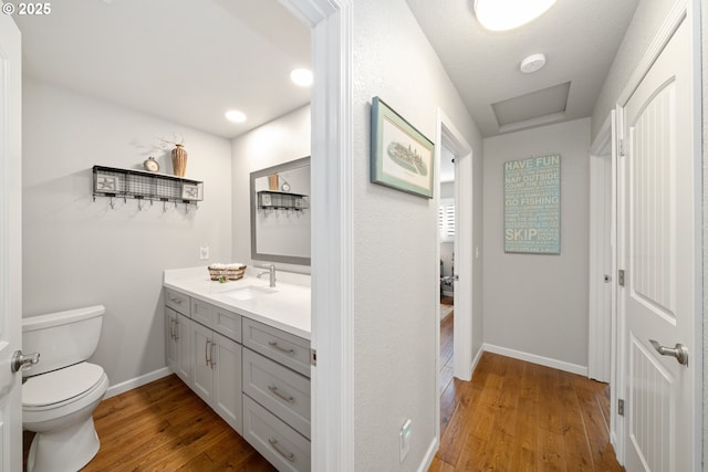 bathroom with toilet, baseboards, wood finished floors, and vanity