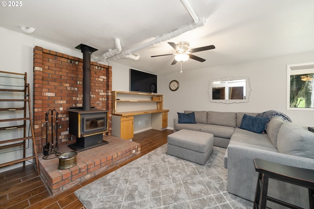 living room with a wood stove, wood tiled floor, baseboards, and ceiling fan