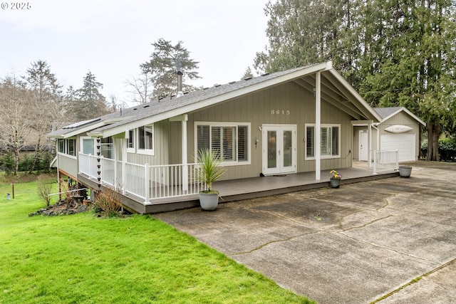 view of front facade with an outbuilding, a deck, a garage, french doors, and a front yard