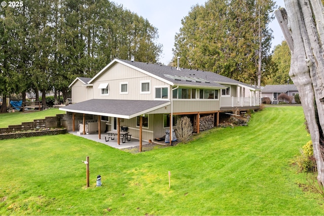 back of house featuring roof with shingles, a lawn, and a patio