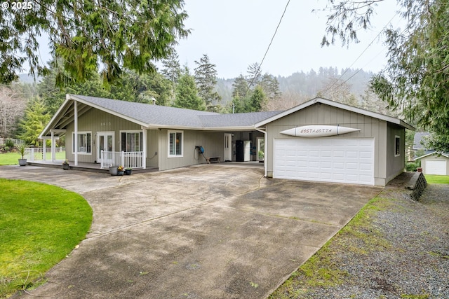 single story home with a shingled roof, concrete driveway, an attached garage, a porch, and a front yard