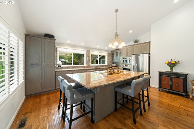 kitchen with a breakfast bar area, dark wood-type flooring, a center island, decorative backsplash, and glass insert cabinets