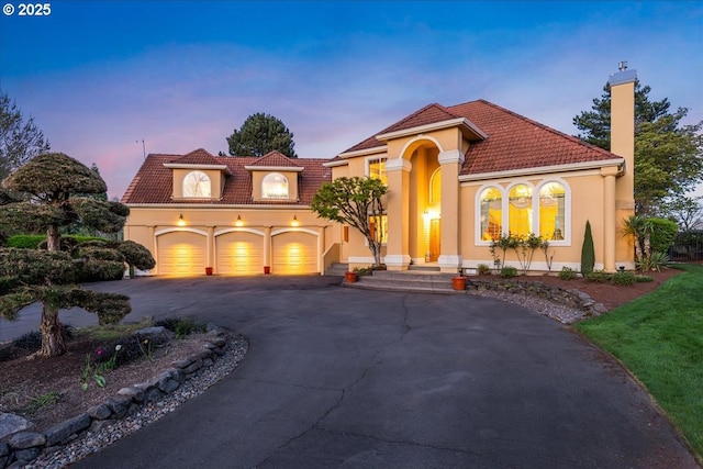 300 SE Arrow Creek Ln, Gresham, OR 97080 - mediterranean / spanish-style house with driveway, a chimney, a tiled roof, stucco siding, and an attached garage