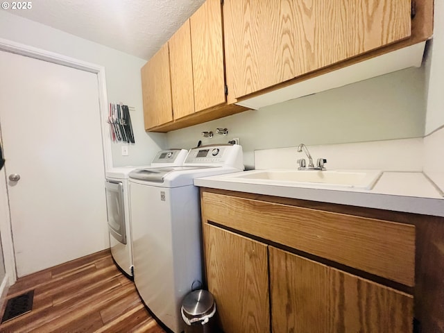 clothes washing area with cabinet space, visible vents, dark wood-style floors, separate washer and dryer, and a sink