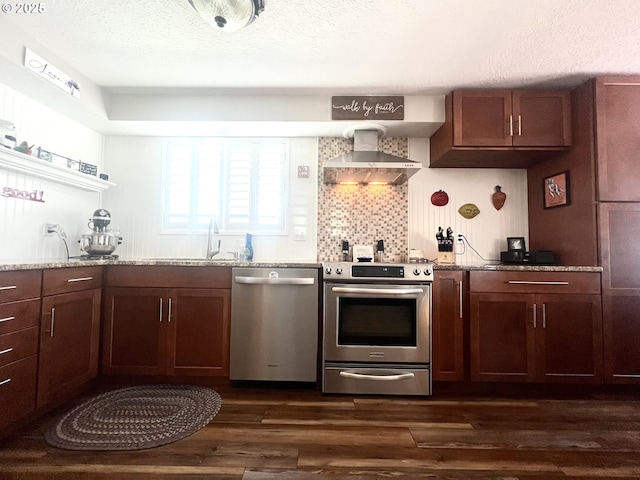 kitchen with a textured ceiling, dark wood-style flooring, appliances with stainless steel finishes, wall chimney range hood, and decorative backsplash