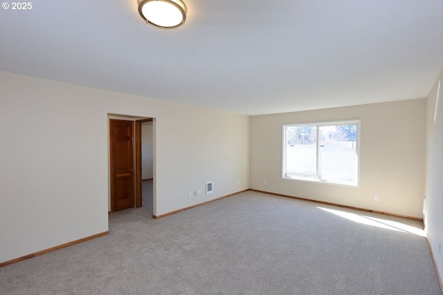 unfurnished room with light colored carpet, visible vents, and baseboards