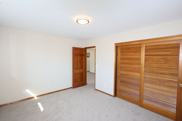 unfurnished bedroom featuring light carpet, a closet, freestanding refrigerator, and baseboards