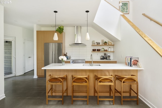 4889 NE Going St, Portland, OR 97218 - kitchen with wall chimney range hood, stainless steel refrigerator, tasteful backsplash, light countertops, and hanging light fixtures