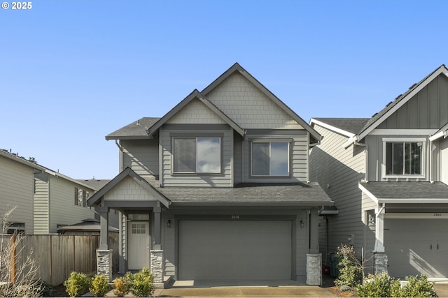 craftsman house with an attached garage, a shingled roof, fence, and board and batten siding