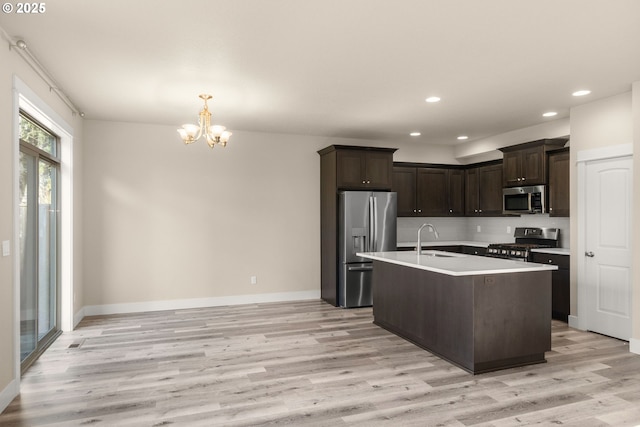 kitchen with stainless steel appliances, light wood-style floors, a sink, and dark brown cabinets