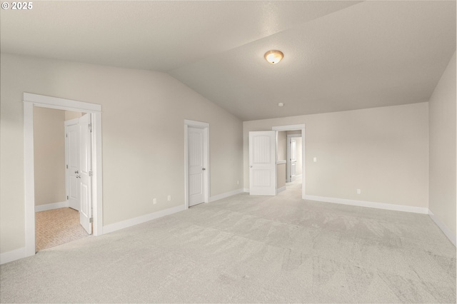 unfurnished bedroom with lofted ceiling, baseboards, connected bathroom, and light colored carpet