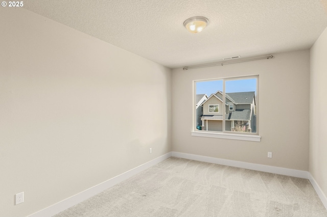 spare room with light carpet, a textured ceiling, and baseboards