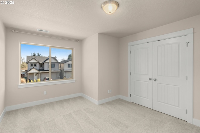 carpeted bedroom with a closet, visible vents, a textured ceiling, and baseboards