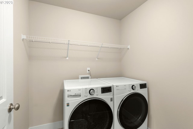 washroom featuring laundry area, baseboards, and washing machine and clothes dryer