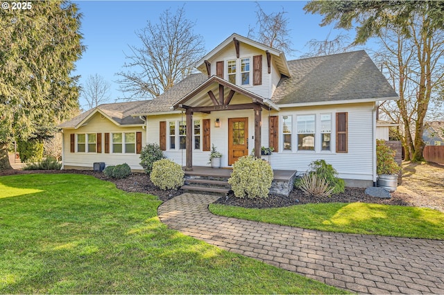 view of front of house featuring fence, a front lawn, and roof with shingles