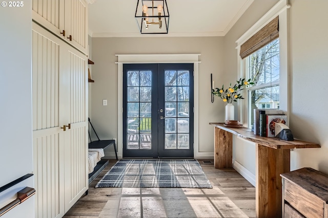 entryway with light wood finished floors, baseboards, crown molding, and french doors