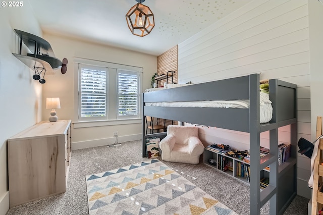 bedroom with carpet floors, wooden walls, and baseboards