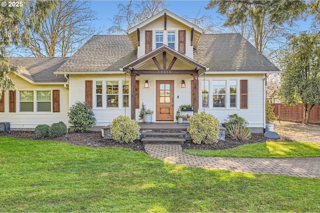 view of front of property featuring roof with shingles, a front yard, and fence