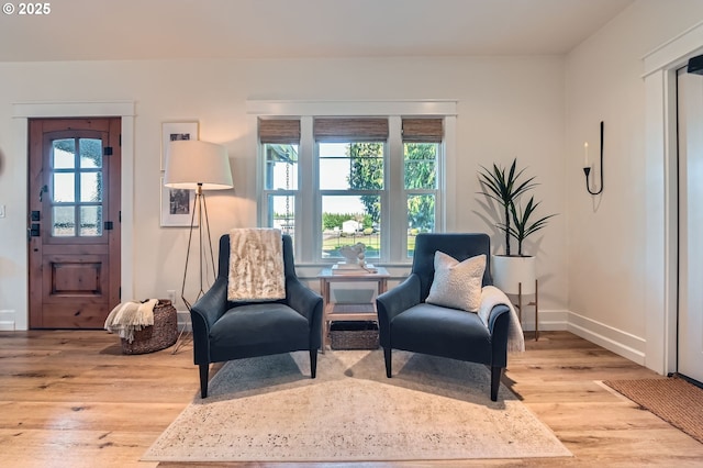 living area featuring baseboards and light wood finished floors