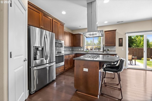 21615 SW Derby Ter, Sherwood, OR 97140 - kitchen with stainless steel appliances, island range hood, dark wood finished floors, dark countertops, and a center island
