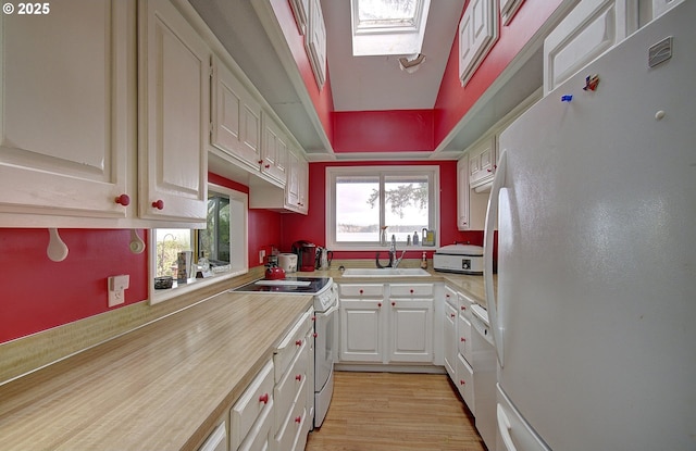 kitchen featuring white cabinetry, sink, white appliances, and a skylight