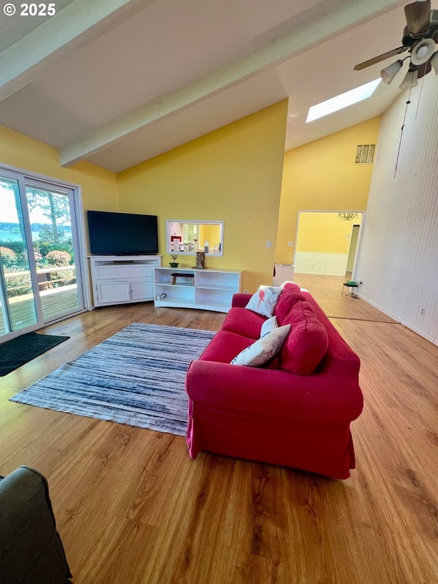 living area featuring a skylight, wood finished floors, ceiling fan, and visible vents