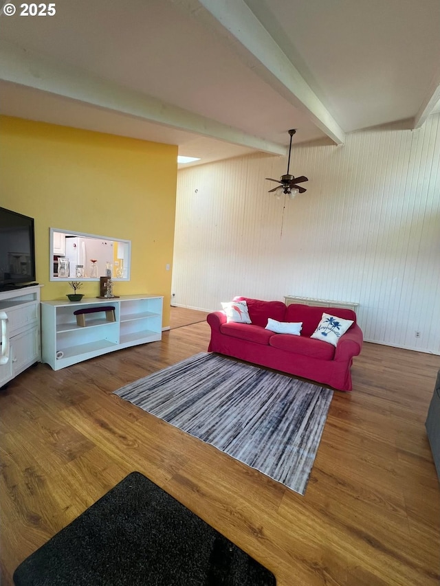 living room featuring ceiling fan, beamed ceiling, and wood finished floors