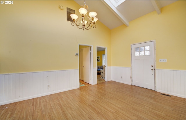 entryway featuring beamed ceiling, a notable chandelier, high vaulted ceiling, and hardwood / wood-style flooring