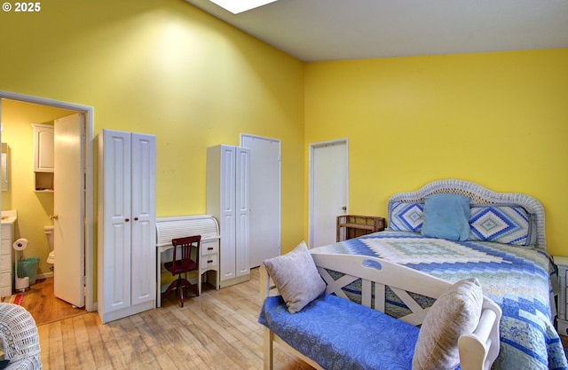 bedroom featuring ensuite bathroom, high vaulted ceiling, and light hardwood / wood-style flooring