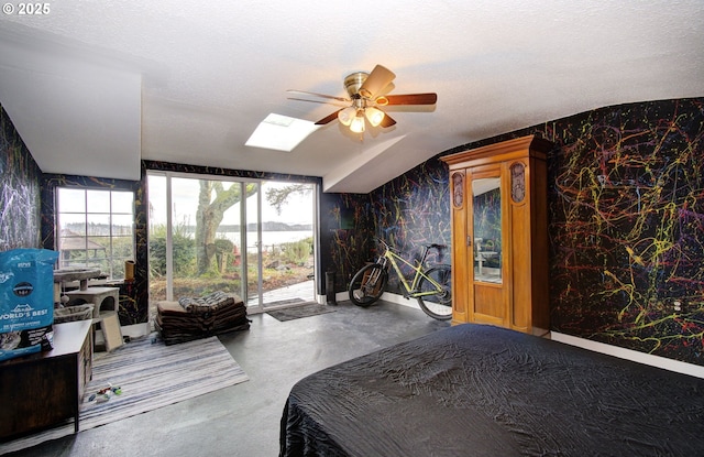 bedroom featuring concrete flooring, a skylight, a textured ceiling, access to outside, and ceiling fan