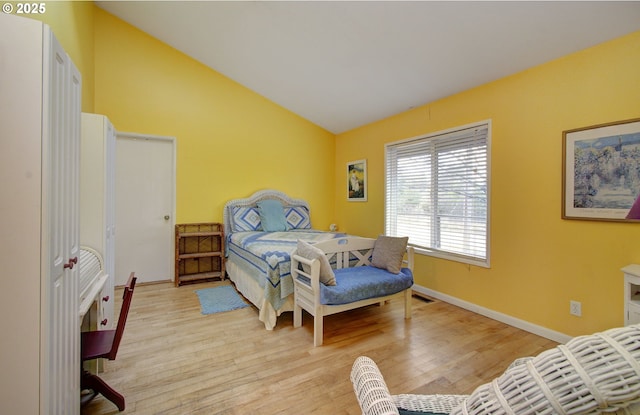 bedroom with light wood-style flooring, visible vents, baseboards, and vaulted ceiling