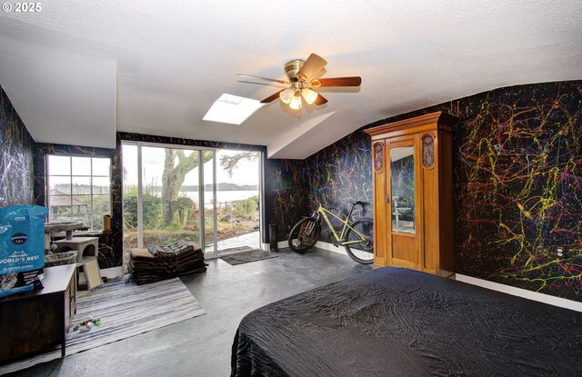 bedroom with a ceiling fan, wallpapered walls, a skylight, access to outside, and finished concrete floors