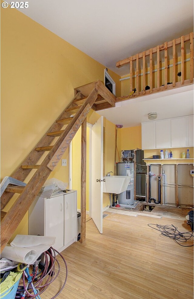 interior space with wood finished floors, a sink, stairs, and water heater