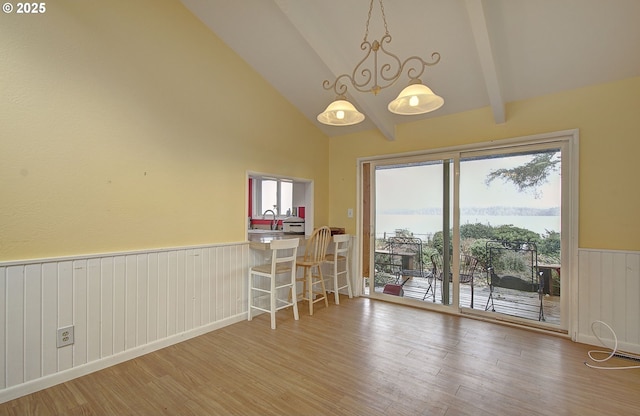 unfurnished dining area featuring beamed ceiling, high vaulted ceiling, and hardwood / wood-style floors