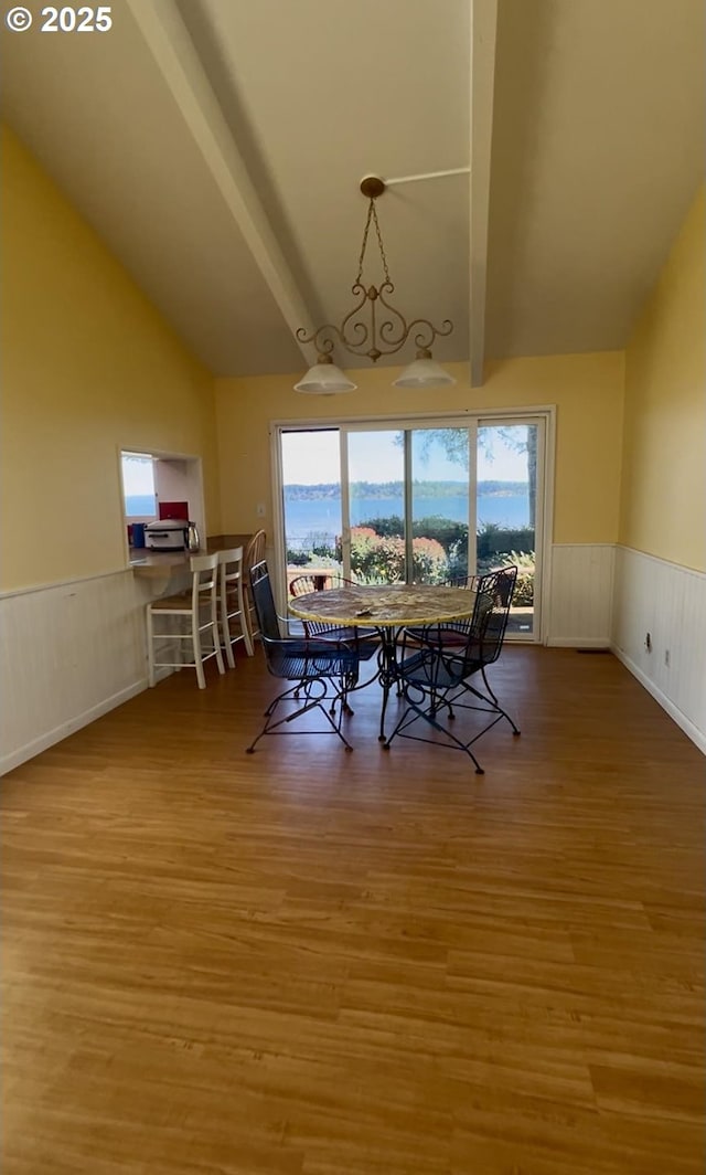 dining space with high vaulted ceiling, light wood-style floors, beam ceiling, and wainscoting