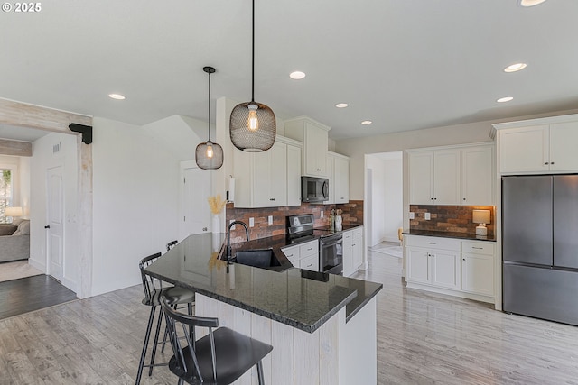 39313 NE 143rd Pl, Amboy, WA 98601 - kitchen featuring a kitchen breakfast bar, tasteful backsplash, a sink, light wood-style floors, and stainless steel appliances