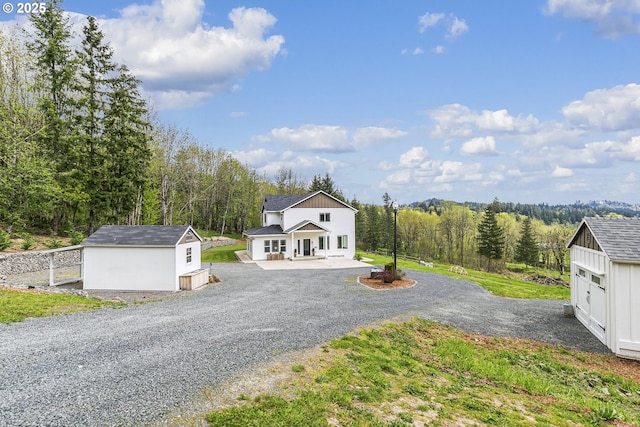 39313 NE 143rd Pl, Amboy, WA 98601 - view of front of home with covered porch, driveway, a storage unit, a view of trees, and an outbuilding