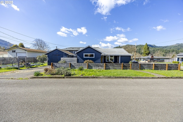 view of front of property featuring a fenced front yard, a detached garage, and aphalt driveway