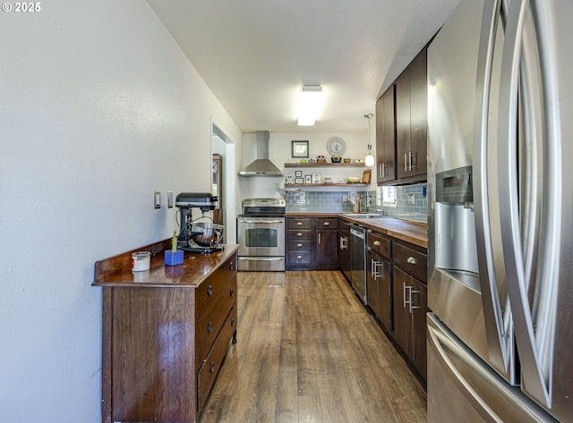 kitchen featuring dark wood finished floors, decorative backsplash, wall chimney exhaust hood, appliances with stainless steel finishes, and open shelves