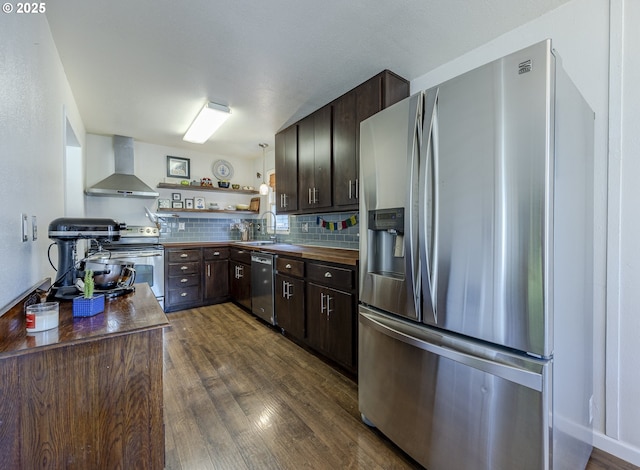 kitchen featuring dark brown cabinetry, stainless steel appliances, open shelves, a sink, and wall chimney exhaust hood