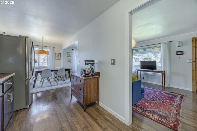 kitchen featuring a textured ceiling, dark wood-style flooring, freestanding refrigerator, and baseboards