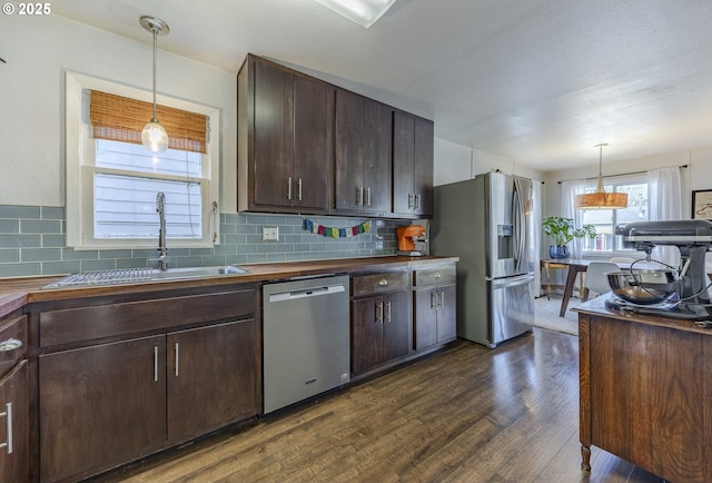 kitchen featuring stainless steel appliances, butcher block countertops, a sink, and dark brown cabinetry