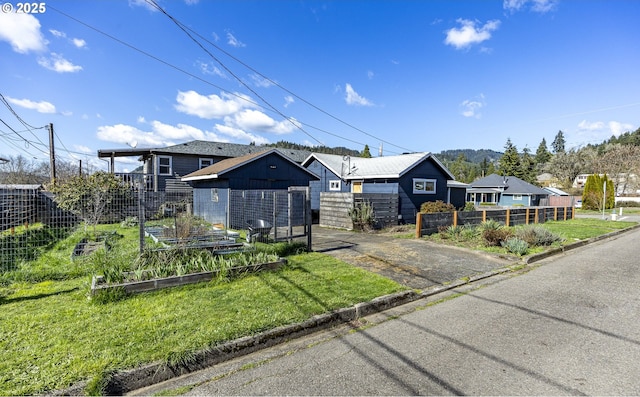 view of front facade with a vegetable garden, a front lawn, and fence