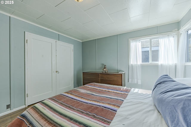 bedroom with wood finished floors and a decorative wall