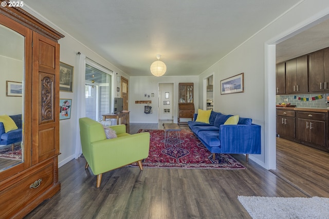 living room featuring dark wood-type flooring, crown molding, and baseboards